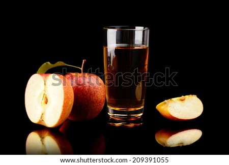 Studio shot of sliced red apple with leaf and apple juice isolated on a black background