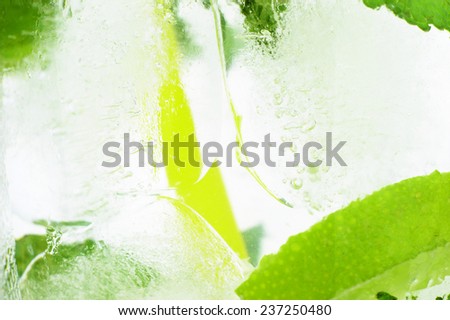 Photo of icy background with close up macro view od drink with ice cubes, mint and limes
