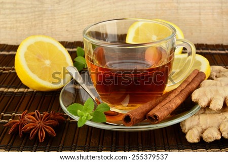 Ginger tea-ingwertee on brown mat with lemon,cinnamon,anise and mint on mat