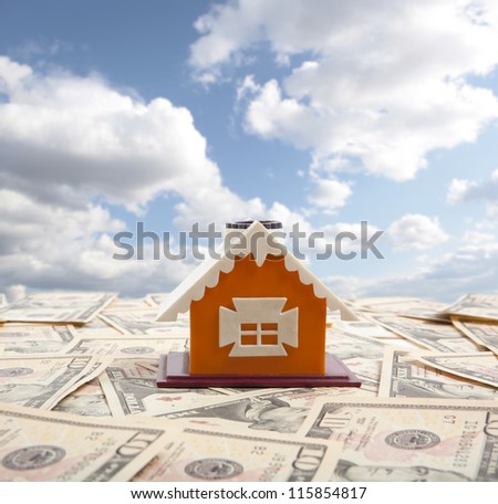 Model of a house with ten dollars on the background