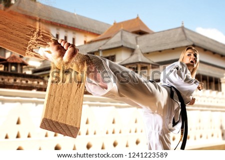 Caucasian female in kimono practicing taekwondo. Breaking board. Modern Korean martial art similar to karate