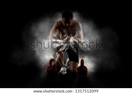 Muscular man clapping hands and preparing for workout at a gym. Focus on dust