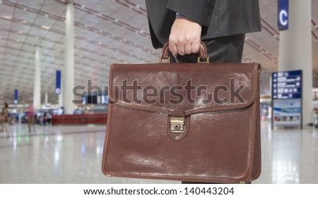 Businessman with a briefcase on a background of departure board at airport