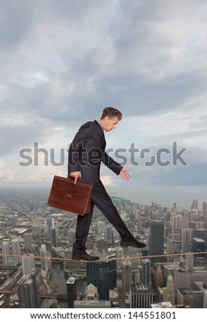 Businessman keeping his balance on a rope over a big city