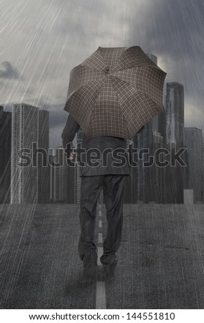 Businessman with umbrella walks in the rain on the background of skyscrapers