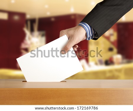 Hand putting a voting ballot in a slot of box