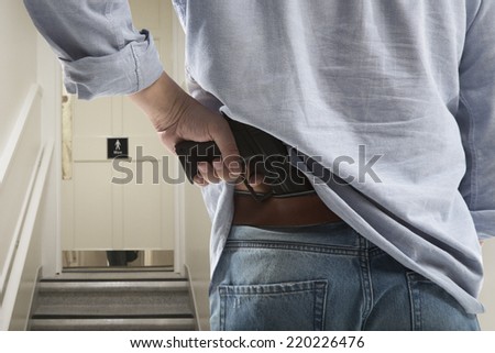 Bodyguard with gun protects client against an s water closet door background