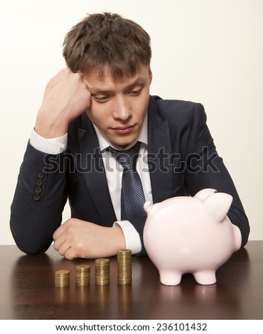 Frustrated businessman looking  pink piggy bank