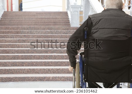Wheelchair user in front of staircase barrier