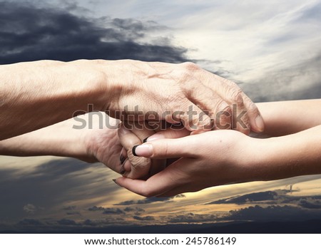 Hands of an elderly senior holding the hand of a younger woman