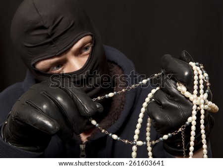 Thief. Man in black mask with a pearl necklace. Focus on pearl necklace
