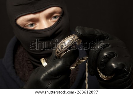 Thief. Man in black mask with a silver bracelet. Focus on bracelet