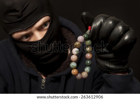 Thief. Man in black mask with a jade necklace. Focus on necklace