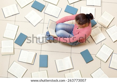 Girl reading a book, top view. Blurred text is unreadable