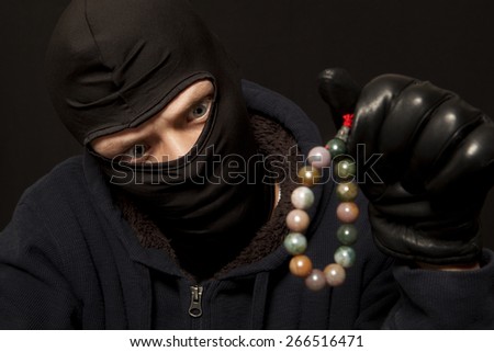 Thief. Man in black mask with a jade necklace. Focus on thief