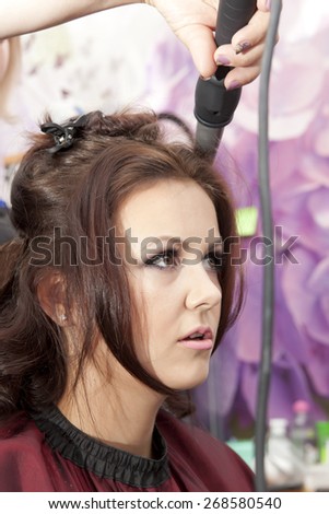 Side view of hairdresser combing hair of female customer before haircut
