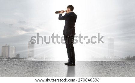 Businessman standing on a on road and looking through a telescope at city