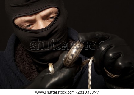 Thief. Man in black mask with a silver bracelet. Focus on thief