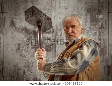 Angry old worker man holding a hammer