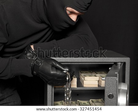 Thief burglar stealing money during home safe codebreaking
