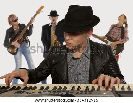 Musical band. Man in the hat playing on a synthesizer