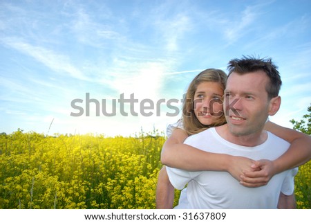 Portrait of young man giving beautiful woman piggyback in the field