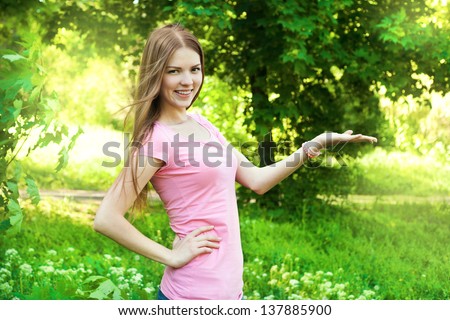 Girl in pink t-shirt showing a product outdoor
