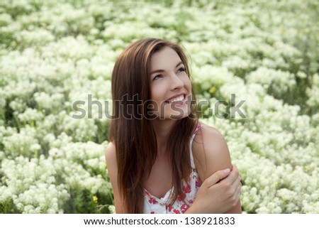 Portrait of beautiful smiling female model at the field of white flowers