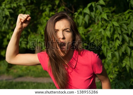 Angry girl shouting and holding her fist, want to attack