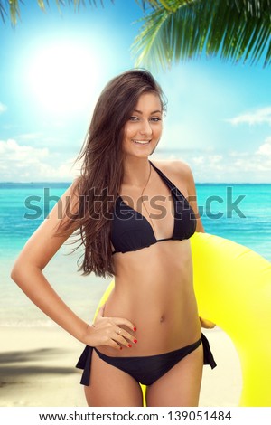 Sexy girl in bikini on the beach holding inflatable circle