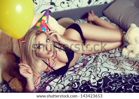A Beautiful Young Blond Woman After Celebrating Her Birthday Lying On The Bed With Balloons And Teddy Bears