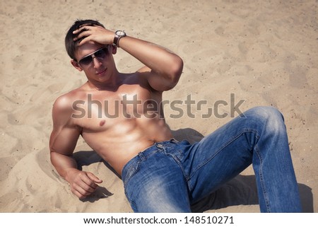 Portrait of an attractive sexy young man lying down at the beach