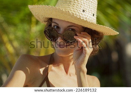 Happy Woman With white Hat and sun glasses At Beach over green palms background