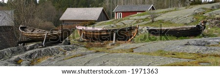Three rowboats on shore in an old fishing village with houses in background, Sweden