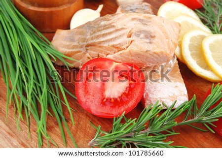 sea food : roasted pink salmon fillet with chinese onion, cherry tomatoes pieces, rosemary twigs and lemon on wooden board isolated over white background
