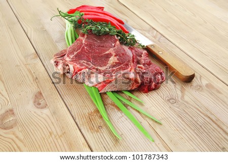 fresh meat : raw beef spare ribs with thyme , red chili pepper , and green onion on wooden board
