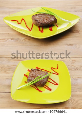 meat food : roasted fillet mignon on green plate with chives and ketchup over wooden table