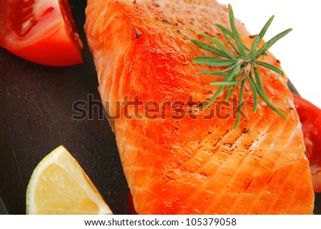 food: roast salmon on metal pan over red wooden plate isolated over white background