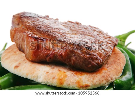meaty food : roast meat steak on arabic pita bread over green hot chili peppers on a white background