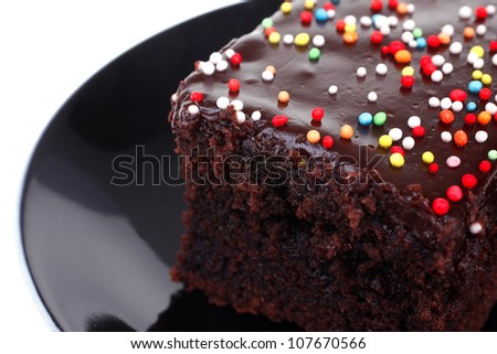 sweet dessert : chocolate cake coated with chocolate on black saucer isolated over white background