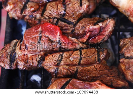 big beef steak on grilling grid over barbecue charcoal