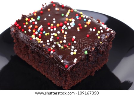 sweet dessert : chocolate cake coated with chocolate on black saucer isolated over white background