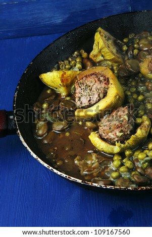 homemade cuisine: zucchini filled meat cooked with peas, beans, on pan over blue