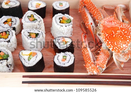 Roll with Cucumber , Cream Cheese with raw Tuna and Salmon inside. on wooden plate with live crab  . Isolated over white background . Japanese traditional Cuisine