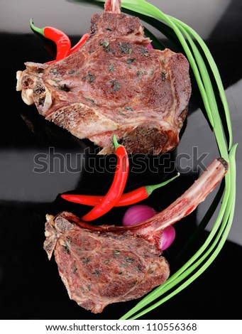 meat savory : roasted beef ribs served with green chives and raw red chili peppers over black plate
