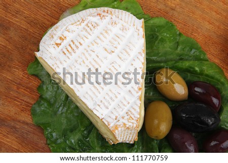 camembert cheese on wooden platter with olives and tomato isolated over white background