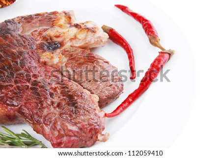 meat food : roasted steak on white plate with red thin chili pepper and spices isolated over white background