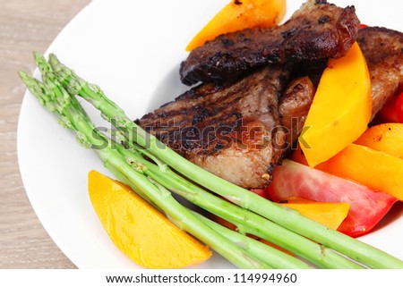 meat food : rare medium roast beef fillet with mango tomatoes and asparagus , served on white dish over wooden table
