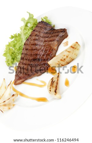 meat food : roast steak boneless with roast onion, served on green lettuce salad on dish isolated over white background