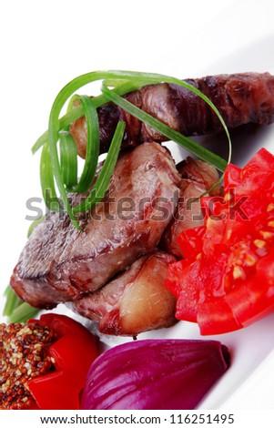 business lunch roasted beef meat strips steak on white ceramic plate with sweet pea and tomatoes isolated over white background